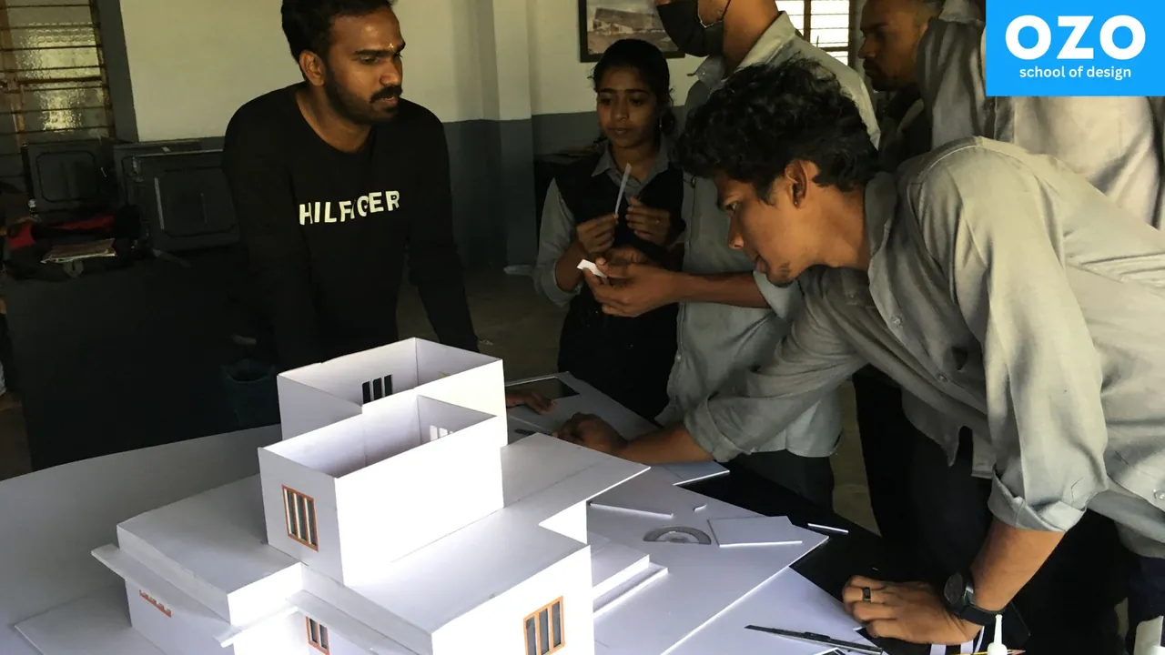 Students and a trainer around a white scale model